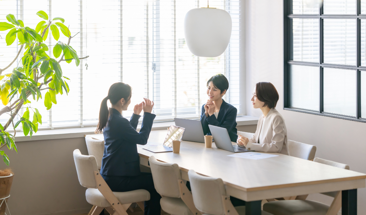 机を囲んでディスカッションをしている女性3名