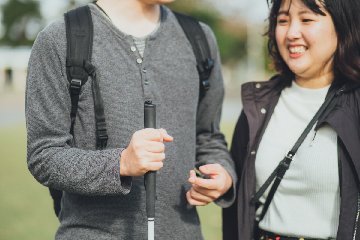 杖を持つ男性と並んで歩く女性